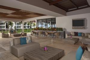 a living room with couches and a table with a tv at Dreams Jade Resort & Spa - All Inclusive in Puerto Morelos