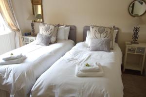 2 camas en una habitación con sábanas blancas y toallas en Mortimer Trail B and B, en Aymestrey