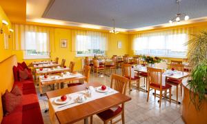 um restaurante com mesas e cadeiras de madeira e paredes amarelas em Golf & Thermenland Sonnenpension Frühstückshotel Burgauberg Stegersbach em Stegersbach