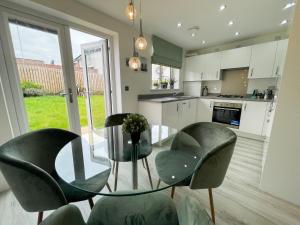 cocina con mesa de cristal y 2 sillas en Newly Developed 3 Bedroom Home en Glasgow