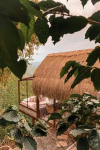 a hut with a bed with a straw roof at Poema Glamping in Palestina