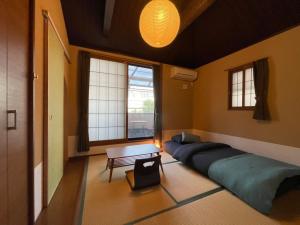 Habitación con cama, mesa y ventanas. en Guesthouse Nobi, en Kioto