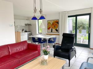 a living room with a red couch and a table at Hello Zeeland - Vakantiehuis Stern 263 in Breskens