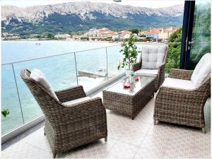 a balcony with chairs and a table and a view of the water at Apartments Palada 1 in Baška