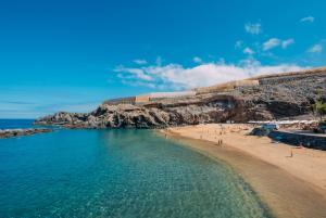 a beach with a group of people in the water at Los Jardines de Abama Suites in Guía de Isora
