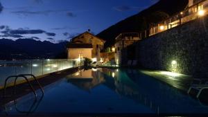 een zwembad 's nachts met een gebouw op de achtergrond bij The Cozy Nest - Bellano in Bellano