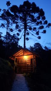 a wooden cabin with a light on it at night at Chalés Canto do Pavão in Visconde De Maua