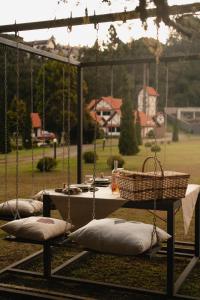 três almofadas num baloiço com uma mesa e uma cesta em Pousada Röhsler em Monte Verde