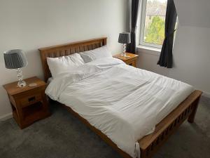 a bedroom with a large bed with white sheets and pillows at Premier 3 Bed Flat D in Broxburn