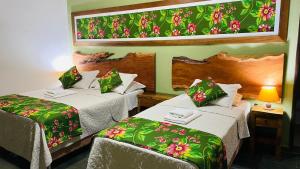 a hotel room with two beds with green and red sheets at SouthWild Pantanal Lodge in Pixaim