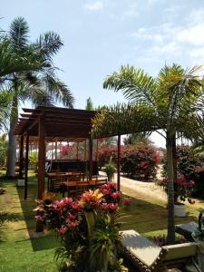um jardim com um pavilhão de madeira com palmeiras e flores em Cucube em Ayangue