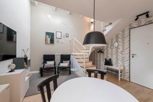 a living room with a staircase and chairs at Brixen City Maisonette in Bressanone