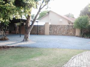 a house with a stone wall and a tree at LightStone Guesthouse in Centurion