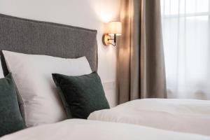 a bed with white sheets and green pillows next to a window at Brixen City Maisonette in Bressanone