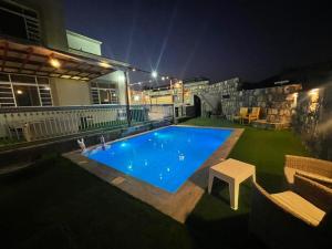 una piscina en medio de un patio por la noche en Al Romaan villa, en Sayq