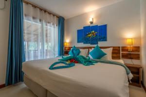 a bedroom with a large white bed with blue accents at Ithaa Dhigurah in Dhigurah