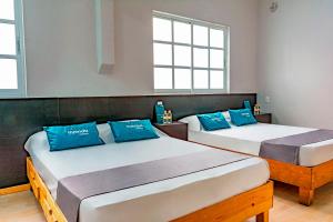 twee bedden in een kamer met blauwe kussens erop bij Ayenda La Selva in Mexico-Stad