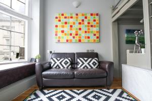 a living room with a leather couch and a painting at Historic two bed apartment in Heart of the City in Bristol