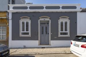 een grijs huis met witte ramen en een deur bij Casa Lobo - 2 bedrooms - Duplex in Faro