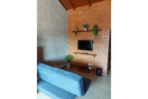 - un salon avec un canapé bleu et un mur en briques dans l'établissement Villa da Serra chalé Ibitipoca - 700m do centrinho, à Conceição da Ibitipoca
