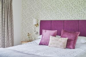 a bed with a purple headboard and purple pillows at Lower Tumble Cottage in Llandyssil