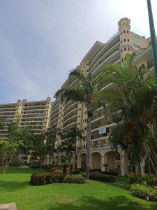 プエルト・バジャルタにあるParadise apartment, private beach condo Bay View Grandのヤシの木が前に生えている大きな建物