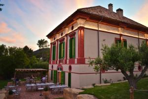 a building with green windows and a patio with tables at Casa Gran 1771 - MontRubí Winery Hotel - Adults Only in Font-Rubí