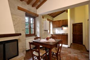 une cuisine avec une table et des chaises ainsi qu'une cheminée dans l'établissement Le Gorghe di Valmarino, à Corciano