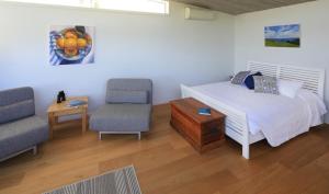 a bedroom with a bed and two chairs and a table at Tutiri in Oneroa in Oneroa