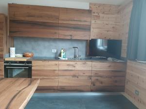 a kitchen with wooden cabinets and a sink at Appartamento Cirmolo in Peio