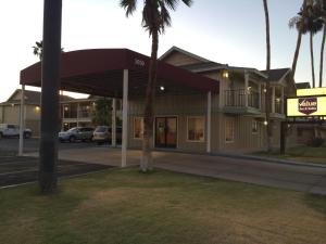 a building on the corner of a street with palm trees at Value Inn & Suites in El Centro