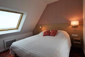 una camera da letto con un letto con due cuscini rossi sopra di Duplex face à l'Océan-Penhors a Pouldreuzic