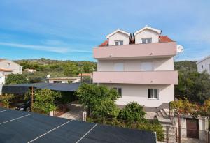 a pink building on top of a parking lot at Apartment Pocrnja in Rogoznica