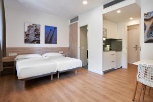 バルセロナにあるアパルトテル アウグスタのベッドルーム(大きな白いベッド1台付)、キッチンが備わります。