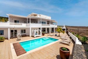 a villa with a swimming pool in front of a house at ODIN LUXURY VILLA by Buenavilla in Puerto Calero