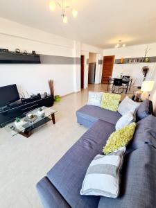a living room with two blue couches and a tv at Stunning apartment C106 with balcony looking over pool in Peyia