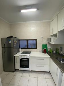 eine Küche mit einem Kühlschrank aus Edelstahl und weißen Schränken in der Unterkunft Apartamento no Guarujá a 400 mts da praia in Guarujá