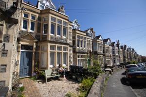 a woman sitting on a bench in front of a row of houses at Bright & Beautiful Studio Flat in Bristol! in Bristol