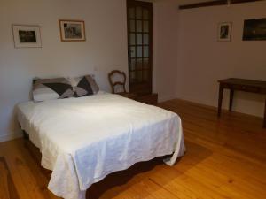 een slaapkamer met een wit bed en een houten vloer bij Gite du jardin du Bout du Ciel in Céron