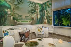サンタニェッロにあるMajestic Palace Hotelの白いテーブルと椅子、壁画のあるレストラン