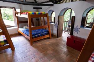 ein Schlafzimmer mit Etagenbetten in einem Zimmer mit Fenstern in der Unterkunft El Refugio Hostel Curití in Curití