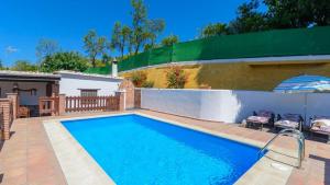 einen Pool im Hinterhof mit einem Zaun und einem Regenschirm in der Unterkunft Casa La Recacha Orgiva by Ruralidays in Órgiva