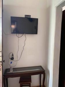 uma televisão de ecrã plano pendurada numa parede por cima de uma mesa em Casa da Tereza em Capitólio