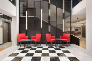 a lobby with red chairs and tables on a checkered floor at Days Hotel by Wyndham Ankara Cankaya in Ankara