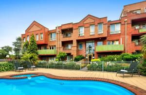 a building with a swimming pool in front of a building at Comfort Apartments Royal Gardens in Melbourne