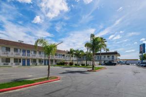a parking lot in front of a hotel with palm trees at Motel 6 Lost Hills / Buttonwillow Racetrack in Lost Hills