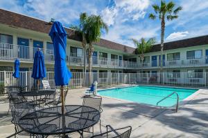 a pool with chairs and umbrellas in front of a hotel at Motel 6 Lost Hills / Buttonwillow Racetrack in Lost Hills