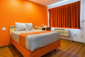 a bedroom with a bed with an orange wall at Motel 6 Lost Hills / Buttonwillow Racetrack in Lost Hills +39 photos