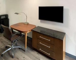 Elle comprend un bureau avec une chaise et une télévision murale. dans l'établissement Rodeway Inn, à Augusta