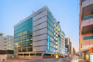 a tall glass building on a city street at Howard Johnson Plaza by Wyndham Dubai Deira in Dubai